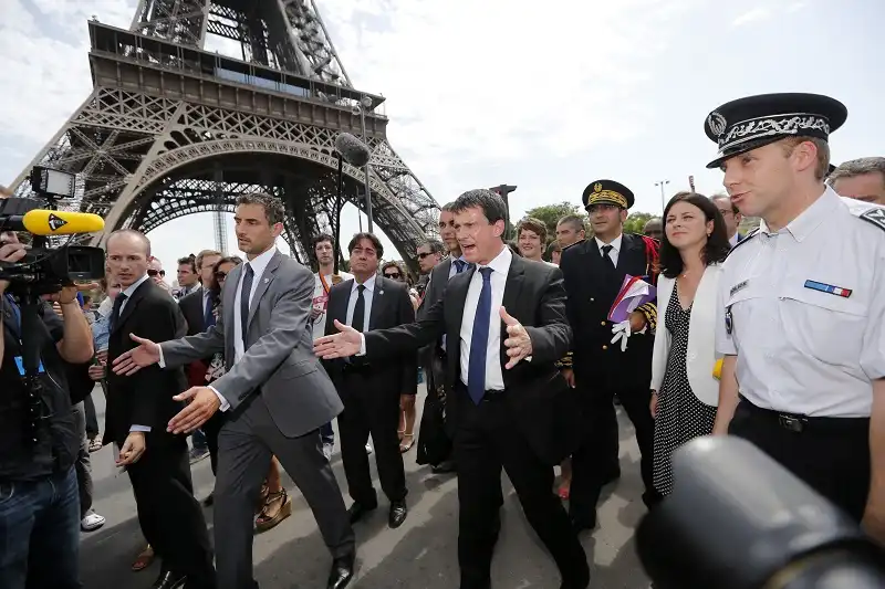 French Interior Minister Manuel Valls (C) gestures as he walks with Junior Minister of Crafts, Business and Tourism Sylvia Pinel (2ndR) and French police surrounded by journalists next to the Eiffel Tower in Paris August 2, 2013 during a tour focused on security at the city's top tourist areas. The French government said on Friday it was working to ensure tourists' safety in Paris as a spate of thefts and muggings threatens to scare wealthy Chinese visitors away from the French capital and its luxury brands. REUTERS/Benoit Tessier (FRANCE - Tags: POLITICS TRAVEL MEDIA)