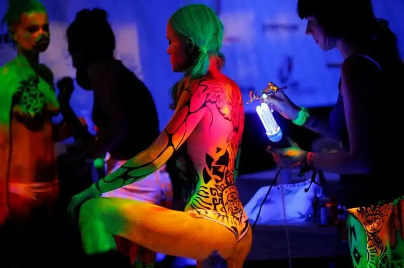 Artist use ultraviolet light paint on models during the World Bodypainting Festival in Poertschach, Austria, July 1, 2016. REUTERS/Heinz-Peter Bader