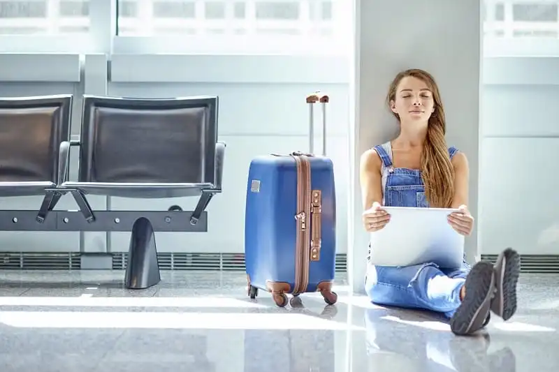 Nên làm gì khi chuyến bay bị delay 5 Shot of a young woman using a laptop while sitting on the floor in an airport