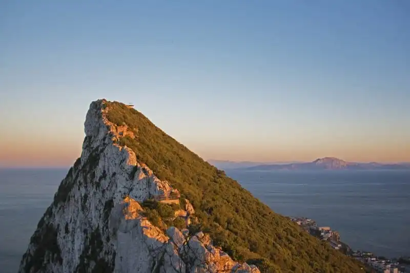 The peak of the Rock, within the nominated property, looking south towards Africa. In the background, beyond the Strait of Gibraltar, lies Jebel Musa on the North African coast. The Rock and Jebel Musa constituted the Pillars of Hercules in ancient times. The vegetation on the slopes of the Rock, within the buffer zone, includes many species known to have been present at the time of the Neanderthals.