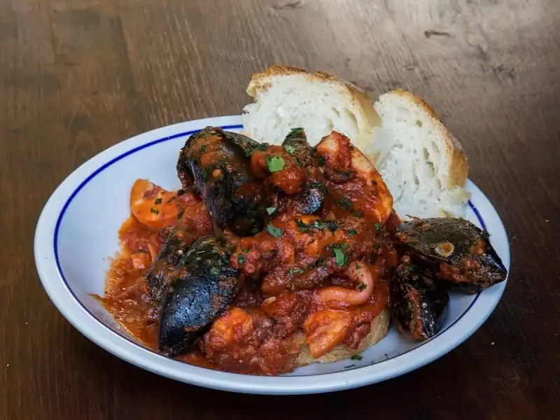 Món hải sản hầm có nguồn gốc từ vùng Livorno, được làm bởi những người bán cá từ những thứ họ bắt được nhưng không thể bán hết như sò, mực, bạch tuộc, ghẹ… Các loại hải sản được nấu trong nhiều cà chua và nước sốt Chile có lá xô thơm, tỏi ăn với bánh mì vỏ cứng.