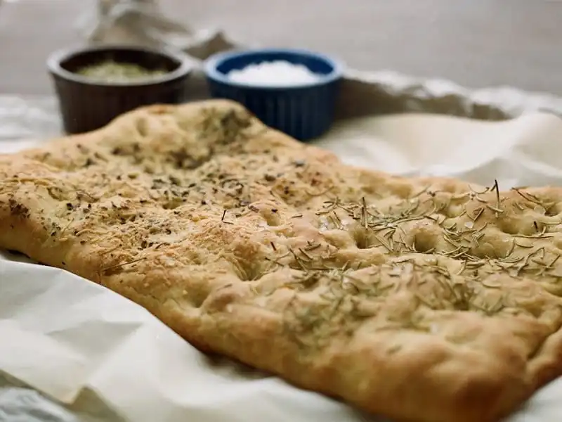 Những chiếc bánh Focaccia có nguồn gốc từ vùng Genova của Italy, có hình chữ nhật đặc trưng, dài khoảng 50cm, kèm thêm chút cà chua, rau thơm và phomai tạo nên những lát bánh mì giòn xốp, thơm ngon cho bữa sáng.