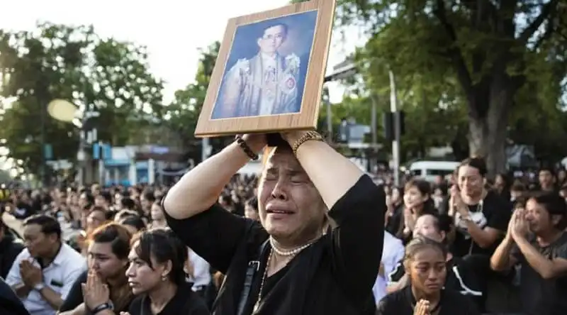 Quốc tang đức vua Thái Lan không ảnh hưởng đến hoạt động du lịch 6 A Thai woman cries as she holds a picture of the late King Bhumibol Adulyadej as others clasp their hands to pay their last respect to a passing van carrying the body of their king outside Grand Palace in Bangkok, Thailand Friday, Oct. 14, 2016. Bhumibol, the world's longest reigning monarch, died on Thursday at the age of 88. (AP Photo/Wason Wanichakorn)