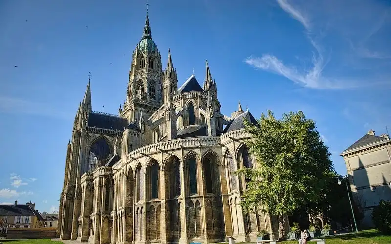 Exterior view Bayeux Cathedral in Bayeux France. Bayeux Cathedral is a Norman-Romanesque cathedral, located in the town of Bayeux. It is the seat of the Bishop of Bayeux. It was the original home of the Bayeux Tapestry and is a national monument of France. The present cathedral was consecrated on 14 July 1077 in the presence of William, Duke of Normandy and King of England. It was here that William forced Harold Godwinson to take the oath, the breaking of which led to the Norman conquest of England.