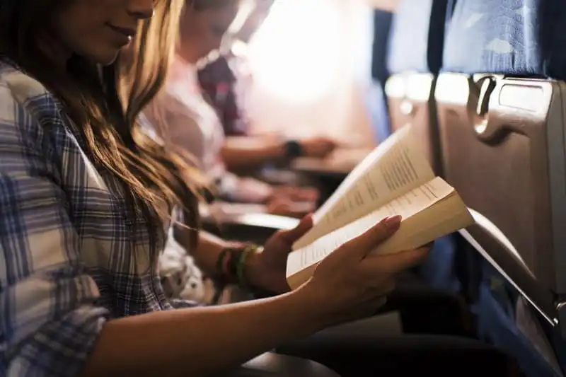 Mẹo đơn giản giúp bạn không bị say máy bay 6 Unrecognizable woman reading a book during her flight.